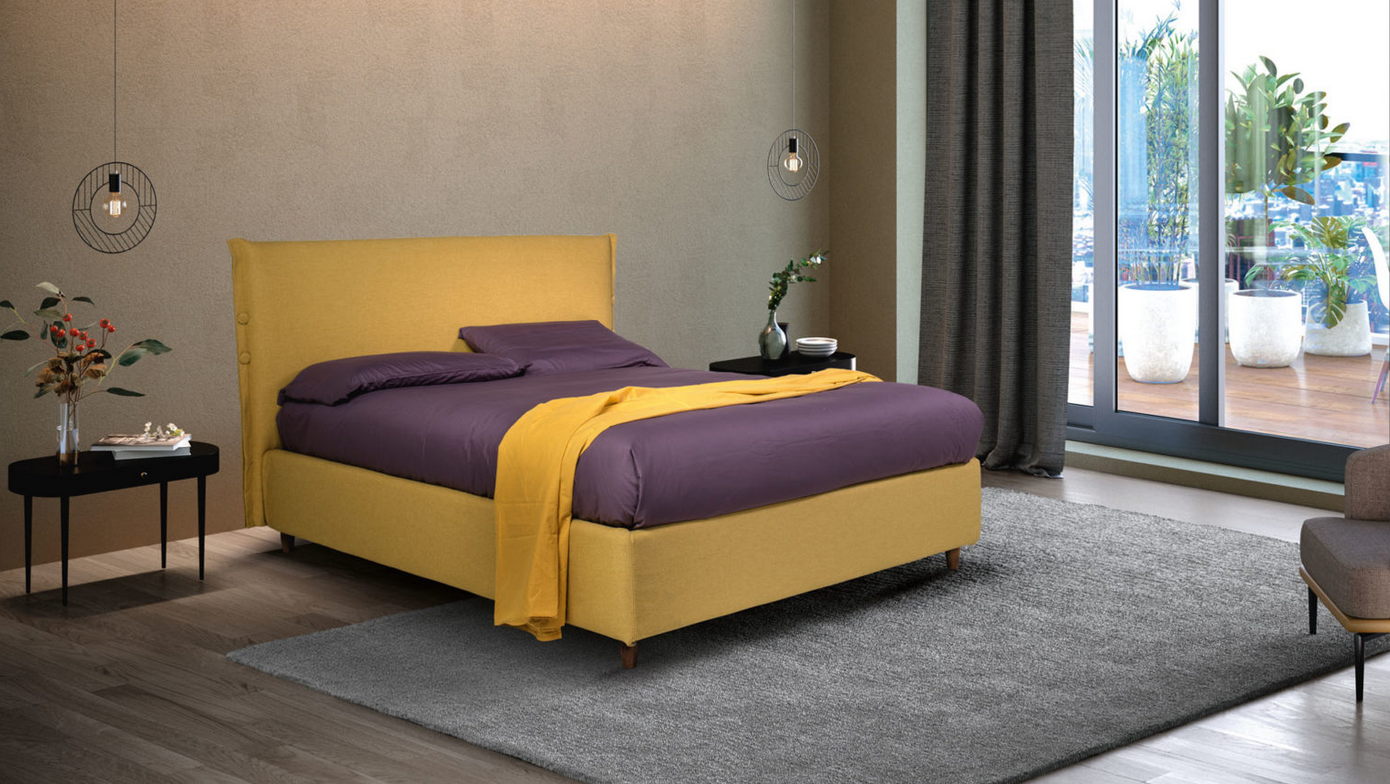 Una camera da letto con un letto giallo e lenzuola viola