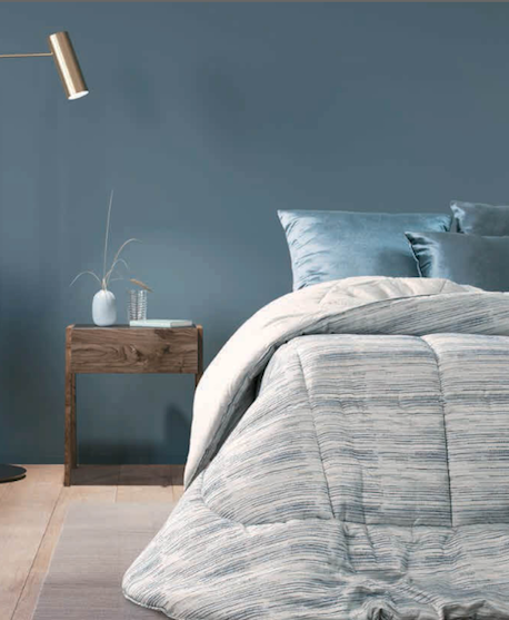Un letto con una trapunta blu e cuscini in una camera da letto