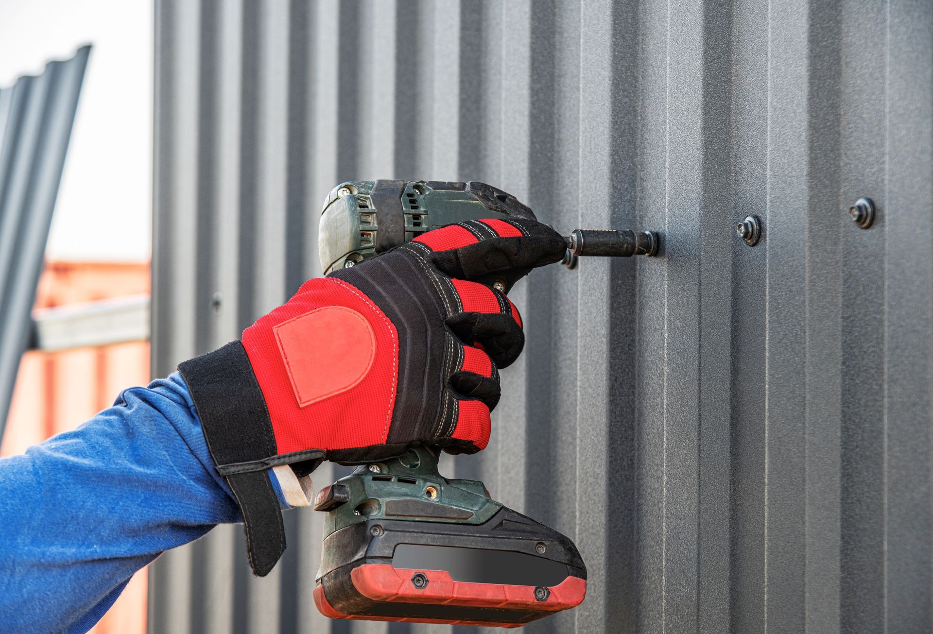 A man is using a drill to screw a screw into a metal wall.