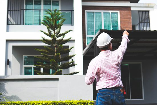 A man in a hard hat is standing in front of a house.