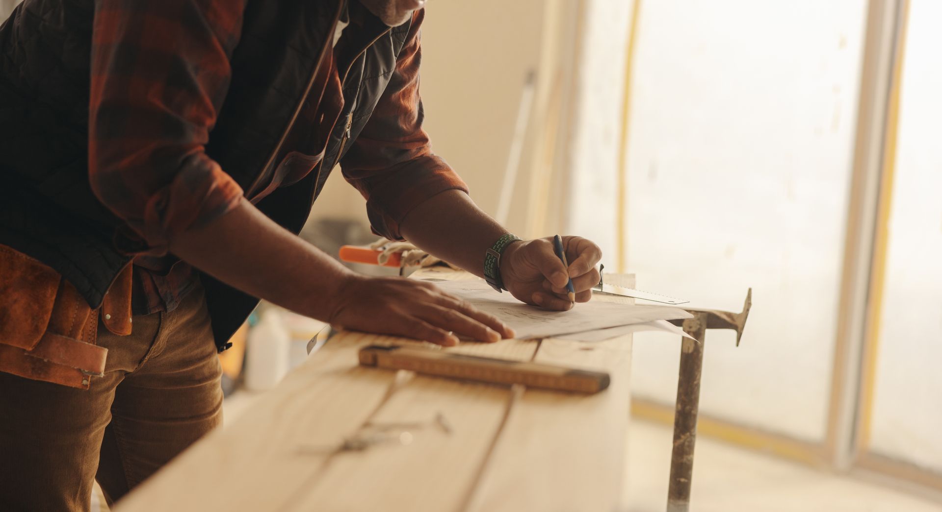 A man is working on a wooden table with a hammer and a piece of paper.