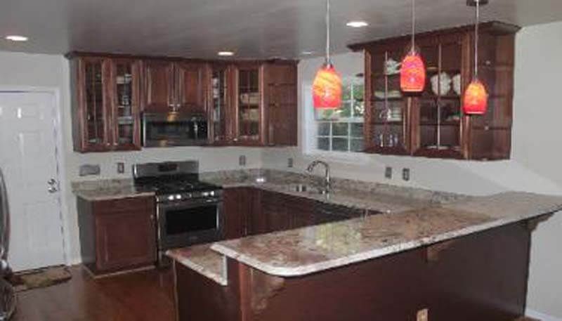 U-shaped kitchen with brown cabinets, granite countertops, and pendant lights.