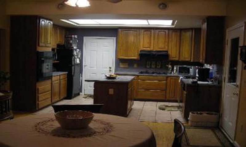 Kitchen with wood cabinets, center island, table, and appliances.