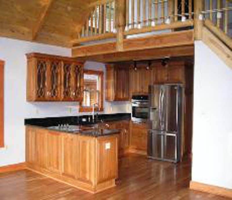 Wooden kitchen with island, black countertops, stainless steel appliances, and a loft.
