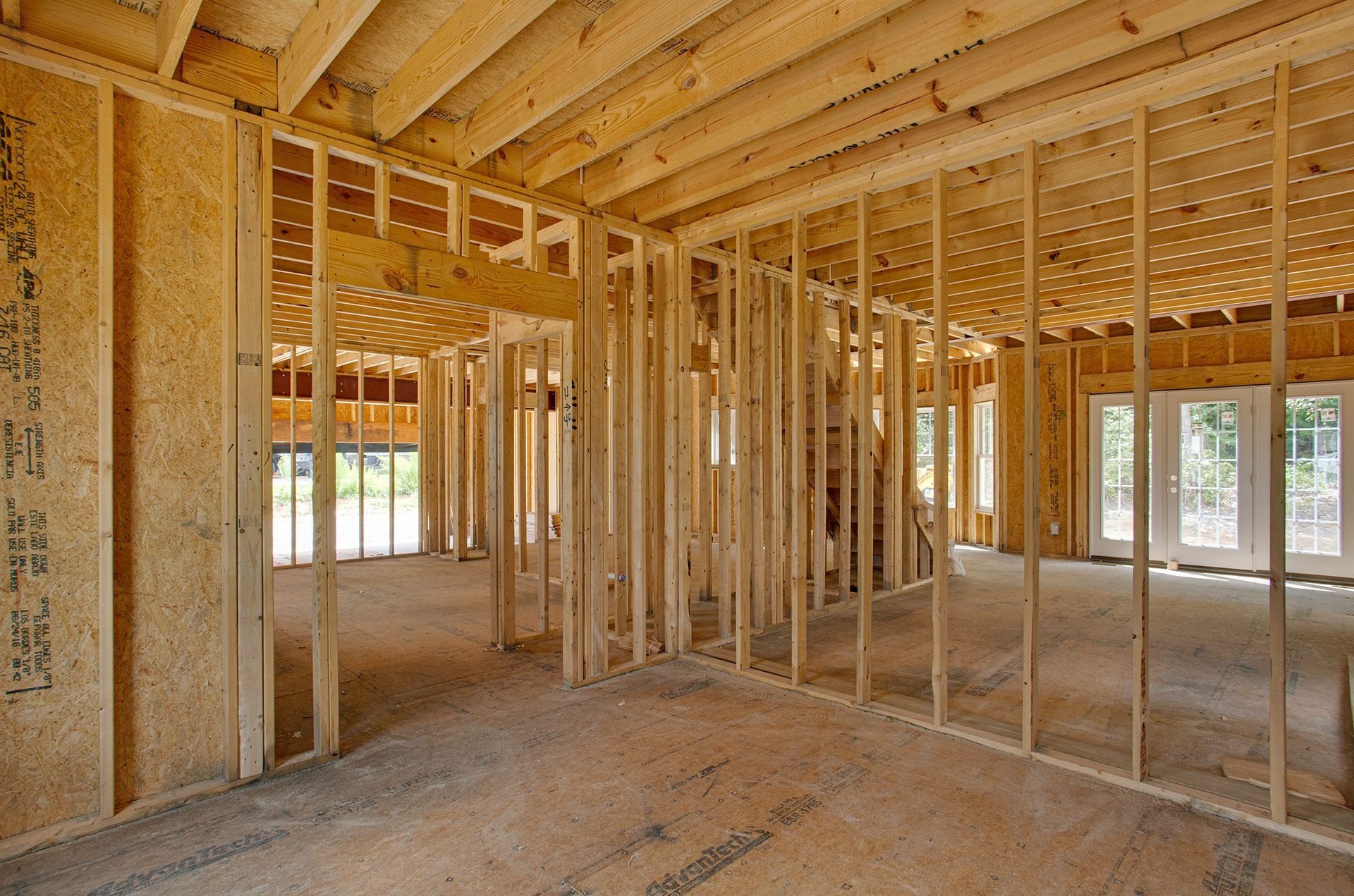 Interior view of a new home under construction with wooden framing and an unfinished floor.