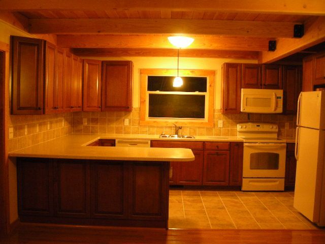 Kitchen with wooden cabinets, beige countertops, and appliances.