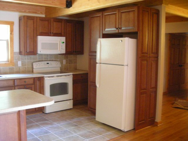 Kitchen with brown cabinets, white appliances, and tiled backsplash.