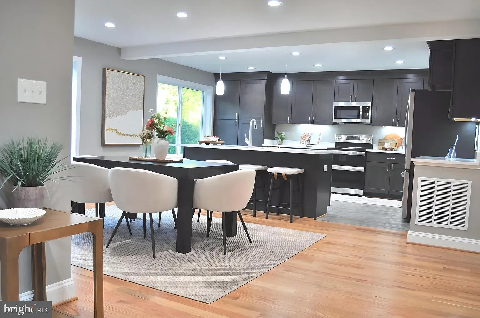 Modern kitchen and dining area with dark gray cabinets, island, and dining table.
