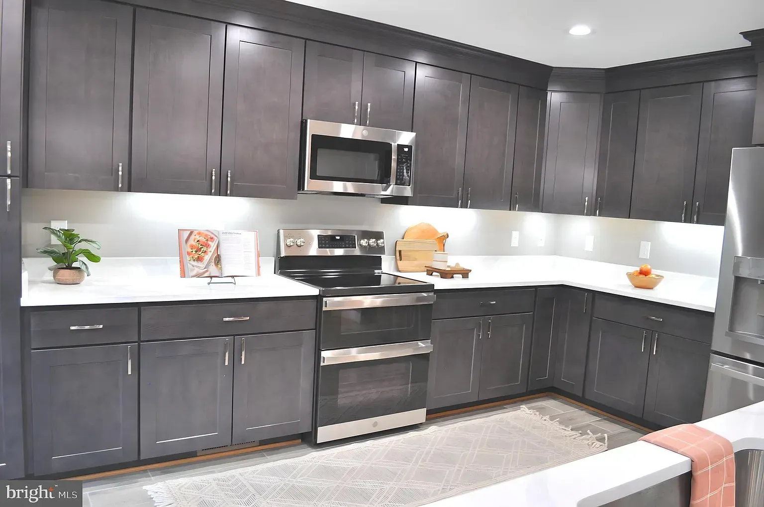 Gray kitchen with white countertops and stainless steel appliances.