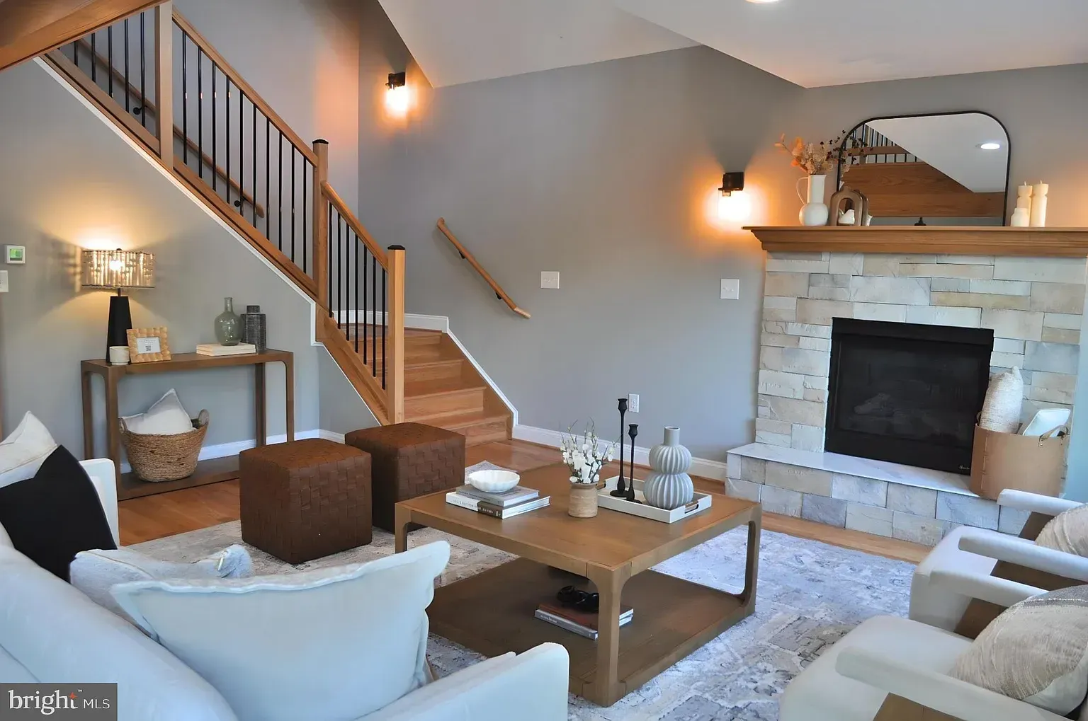 Living room with fireplace, staircase, and seating in a neutral color palette.