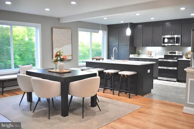 Modern kitchen and dining area with gray cabinetry, island, and dining table; large windows.