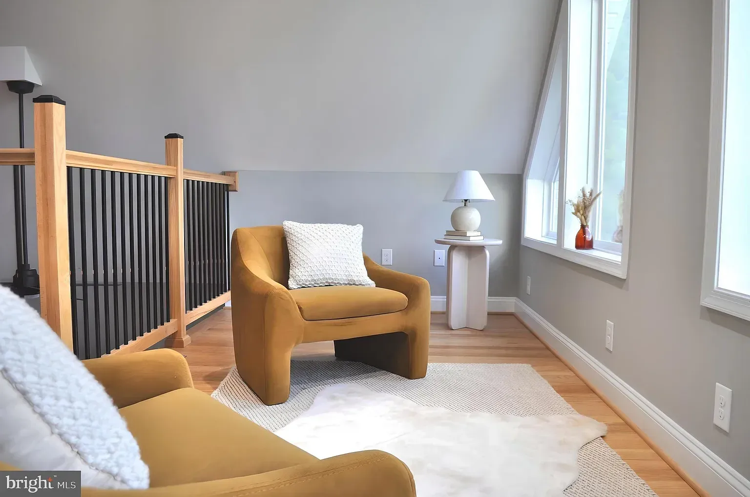 Mustard-yellow armchair in a cozy room with a rug and side table next to a window.