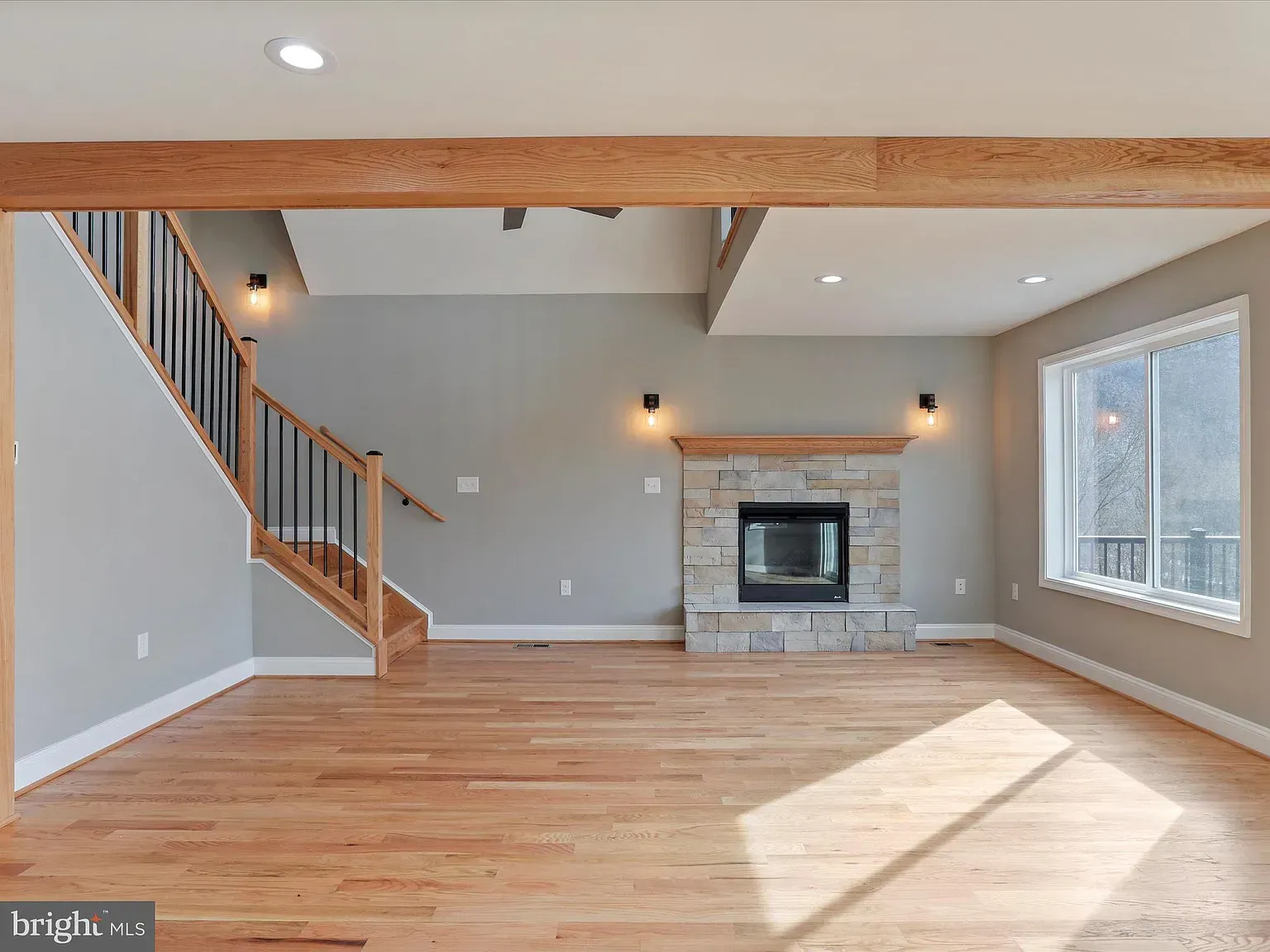 Living room with fireplace, staircase, wood floors, and gray walls.