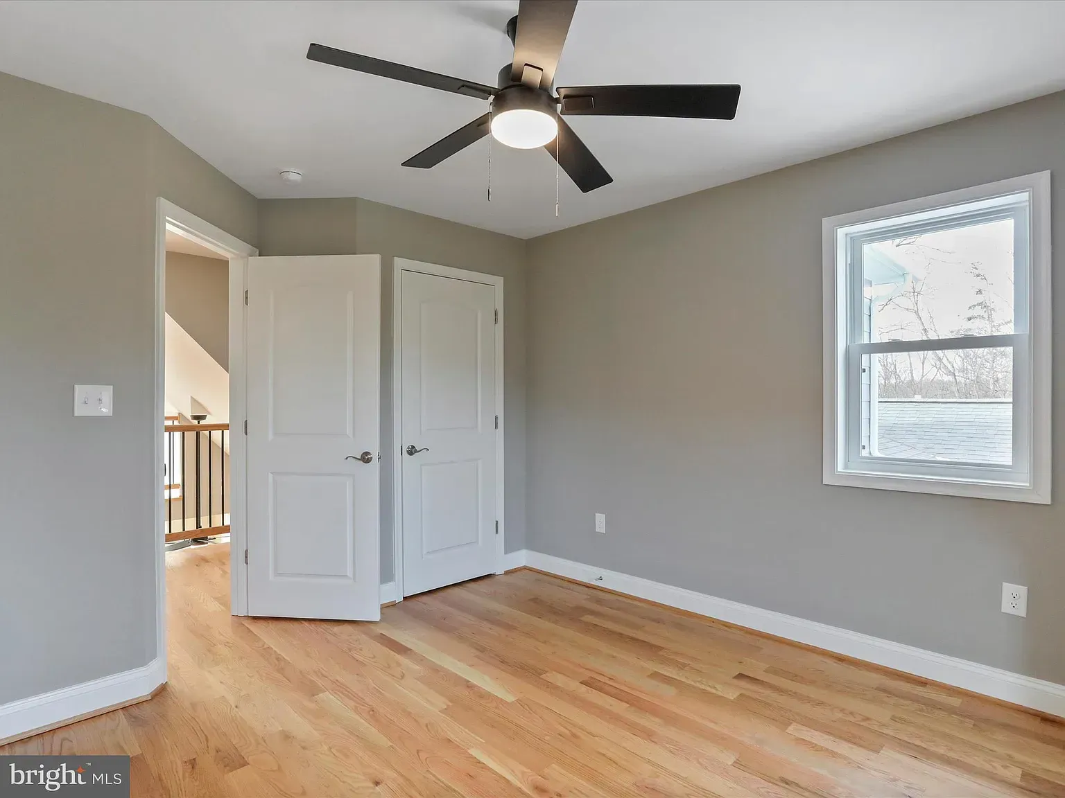 Bedroom with gray walls, hardwood floor, white doors and trim, and a ceiling fan.