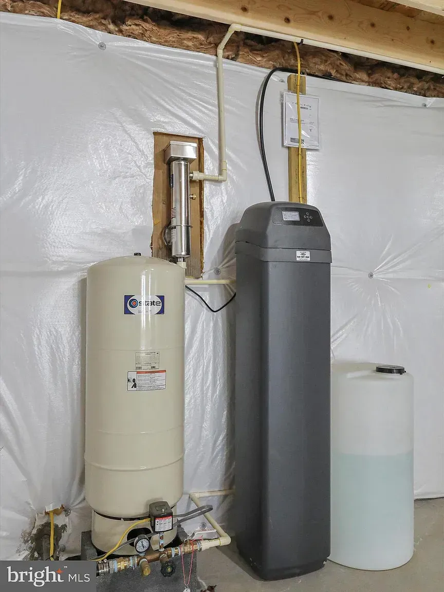 A basement with water treatment system. Includes water tank, water softener, and a brine tank.