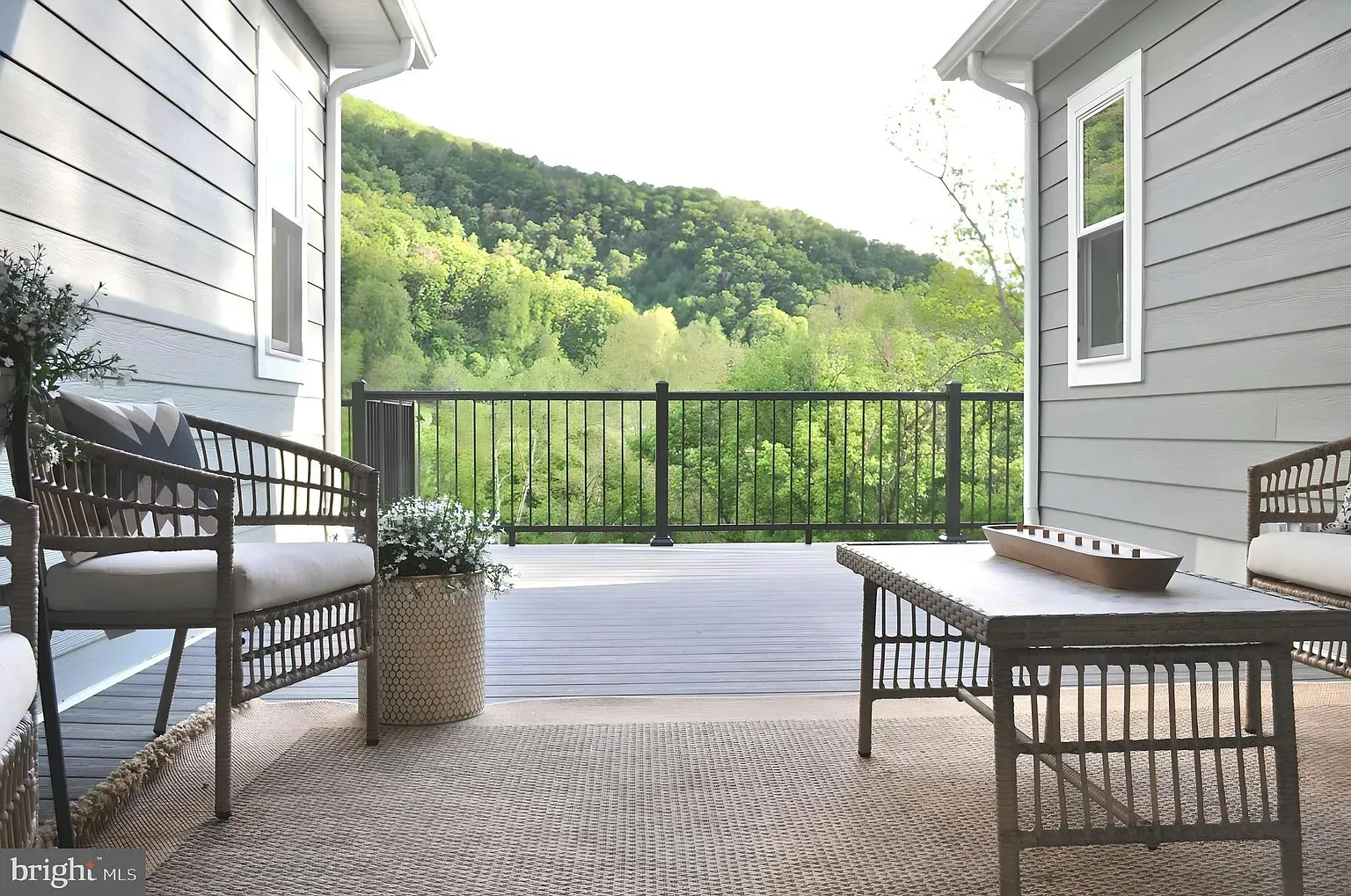 Outdoor deck with seating, mountain view, surrounded by light gray siding.