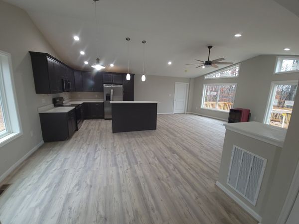 Open-concept kitchen and living area with dark cabinets, stainless steel appliances, and wood-look flooring.