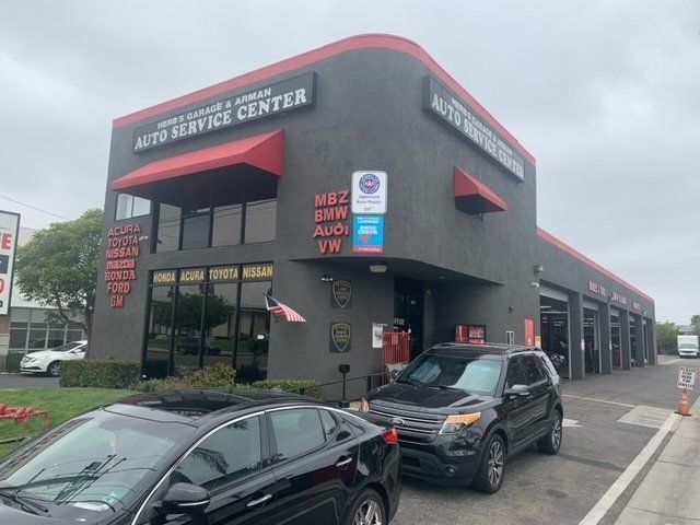 A black car is parked in front of an auto service center