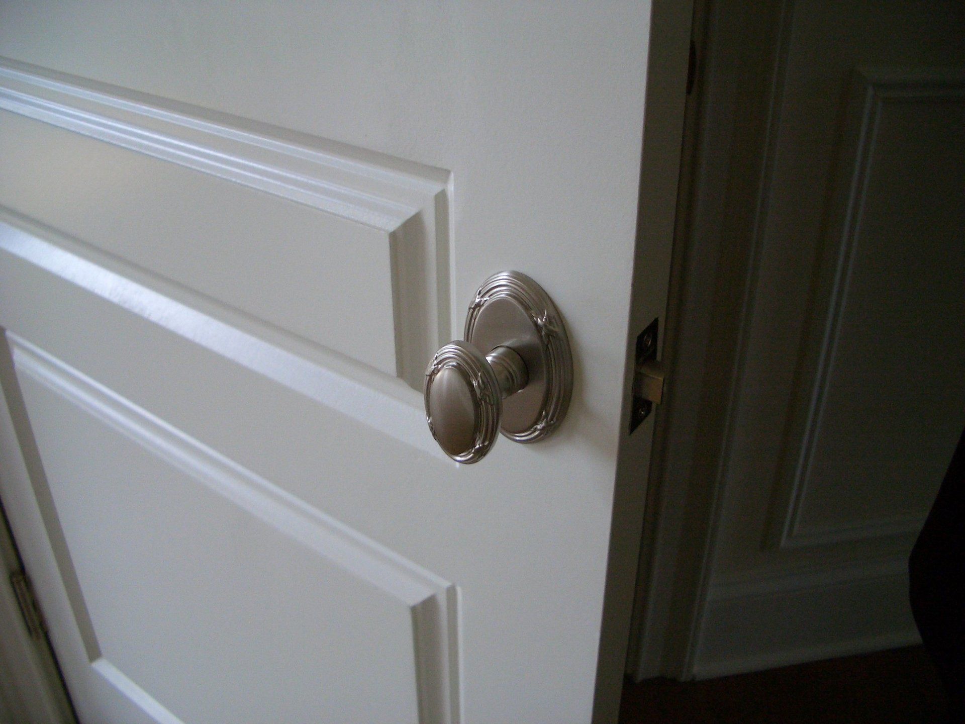 A close up of a door knob on a white door