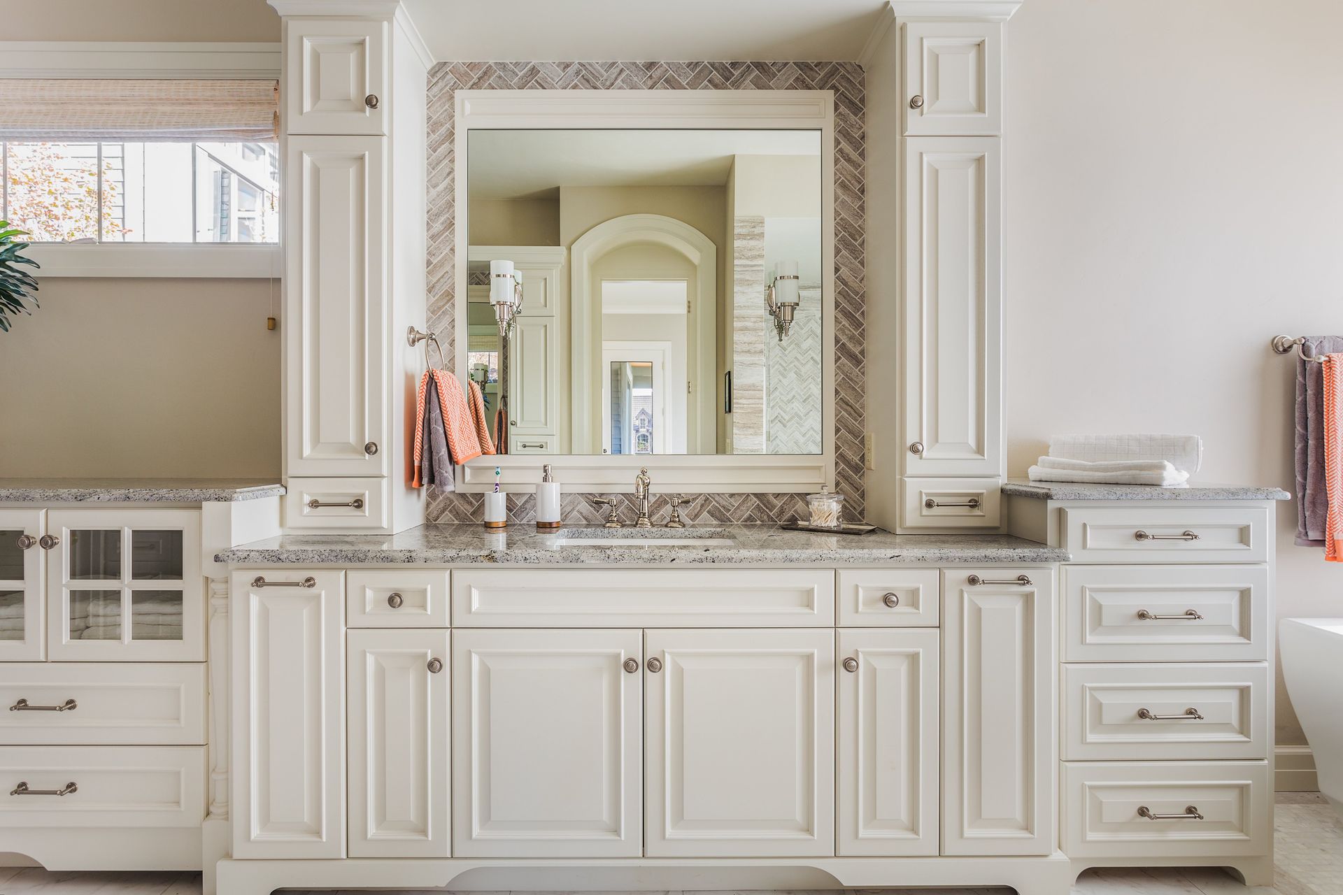 A bathroom with white cabinets and a large mirror.
