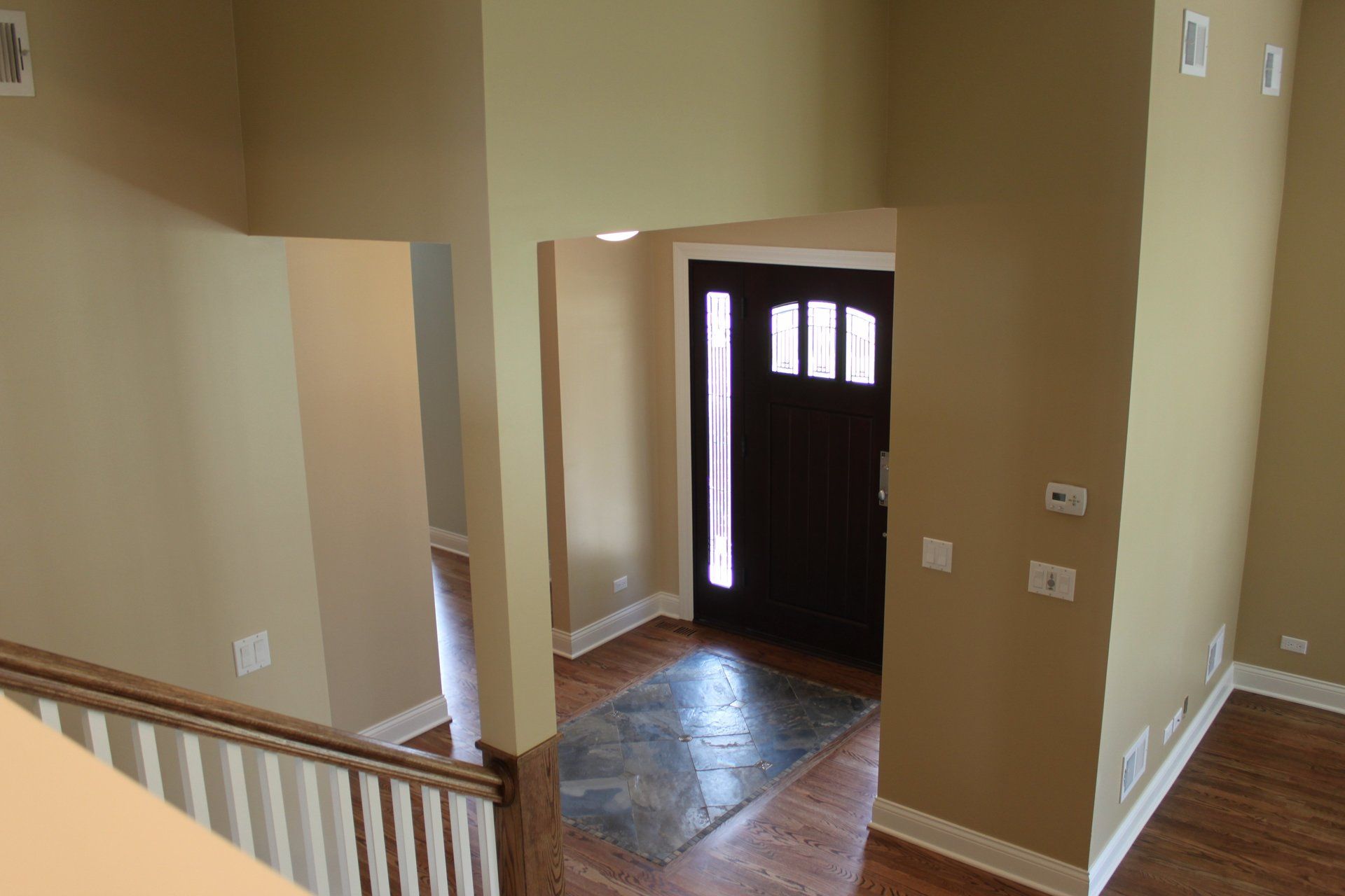 An empty house with a staircase leading to the front door.