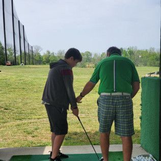 Two men are standing on a golf course holding golf clubs.