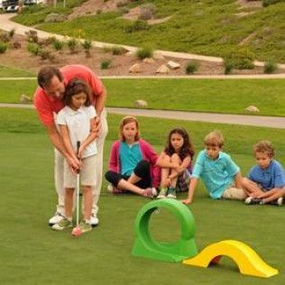 A man is teaching a young girl how to play golf.