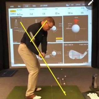 A man is swinging a golf club in front of a large screen