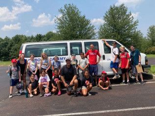 A group of children are posing for a picture in front of a van.