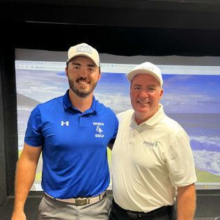 Two men are posing for a picture in front of a golf simulator.