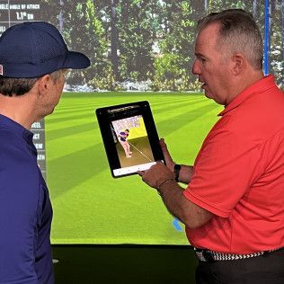 Two men are standing next to each other looking at a tablet.