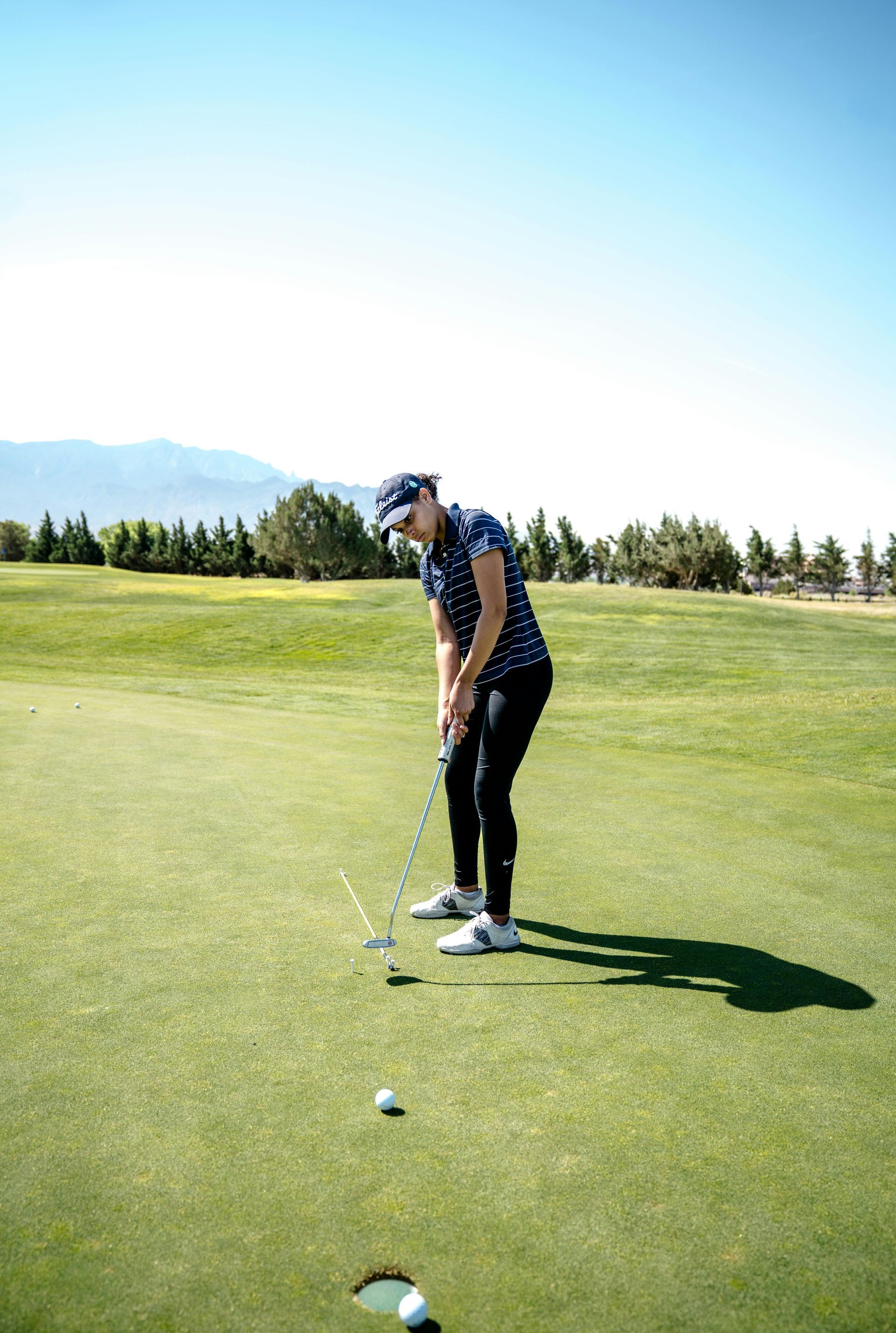 Three golf clubs and a golf ball are on the grass.