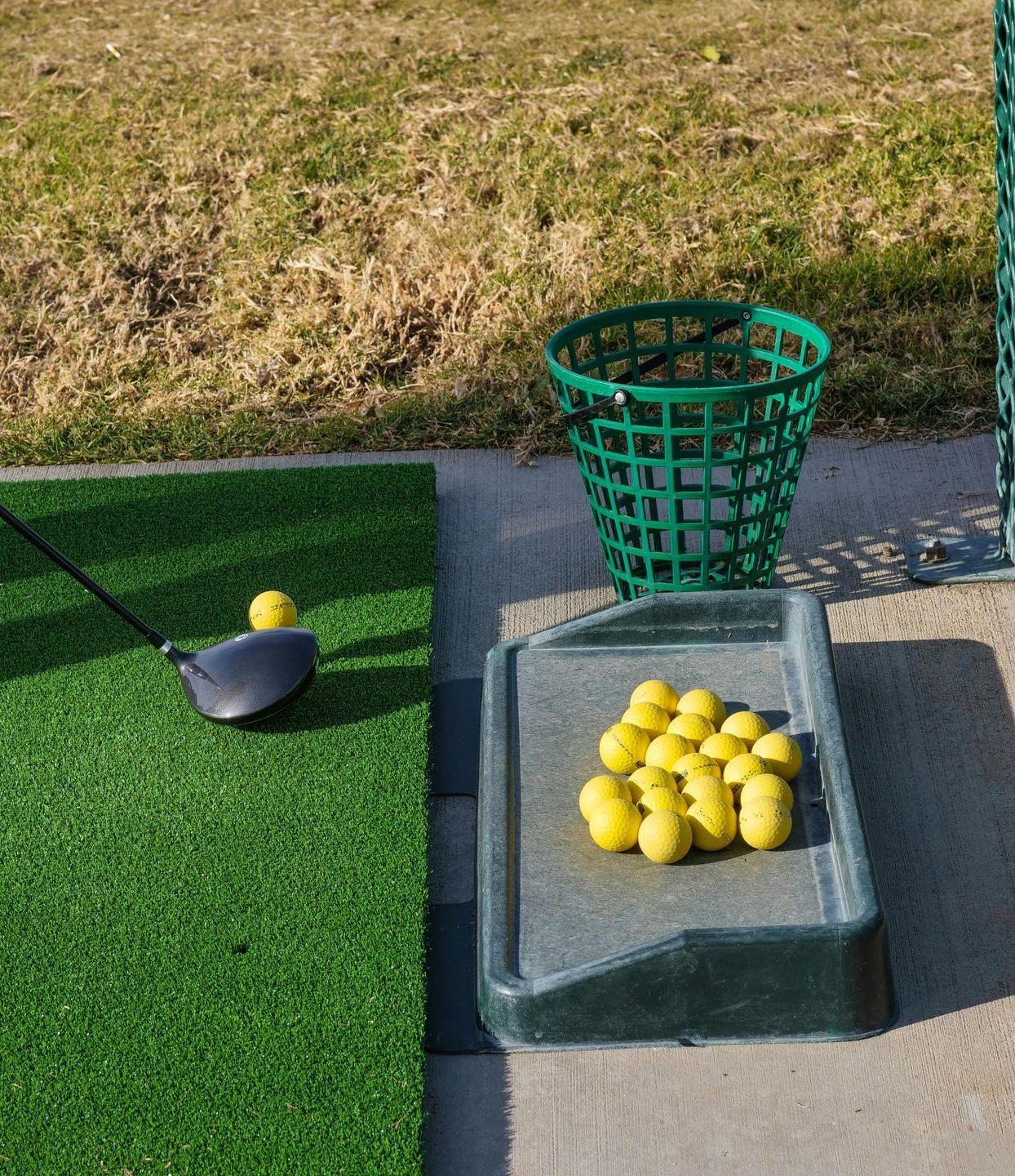 Three golf clubs and a golf ball are on the grass.