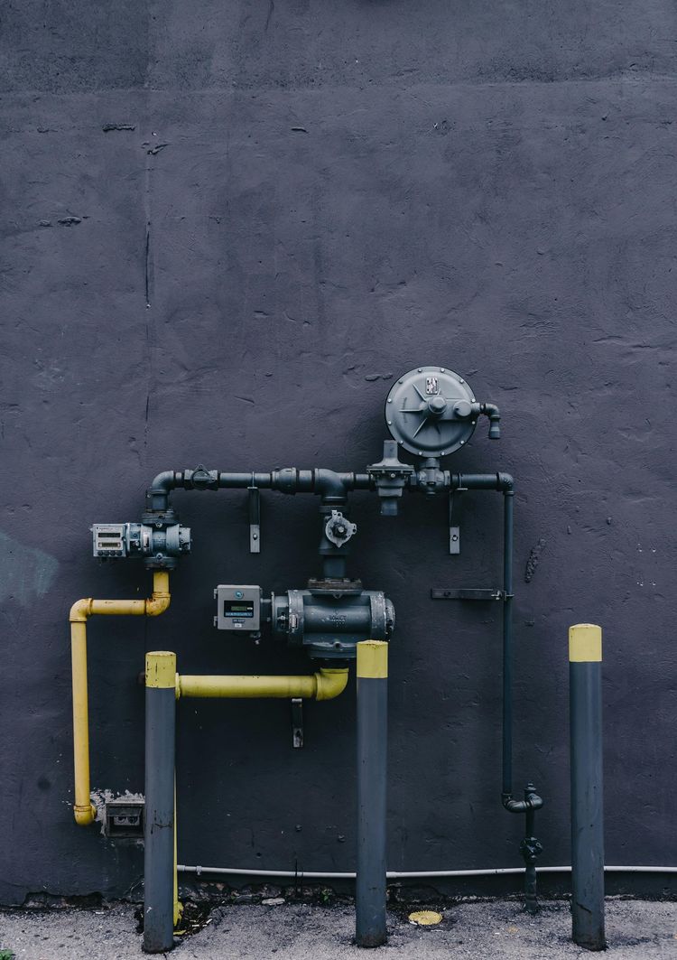Gas pipes and valves against a dark wall, yellow and gray colors.