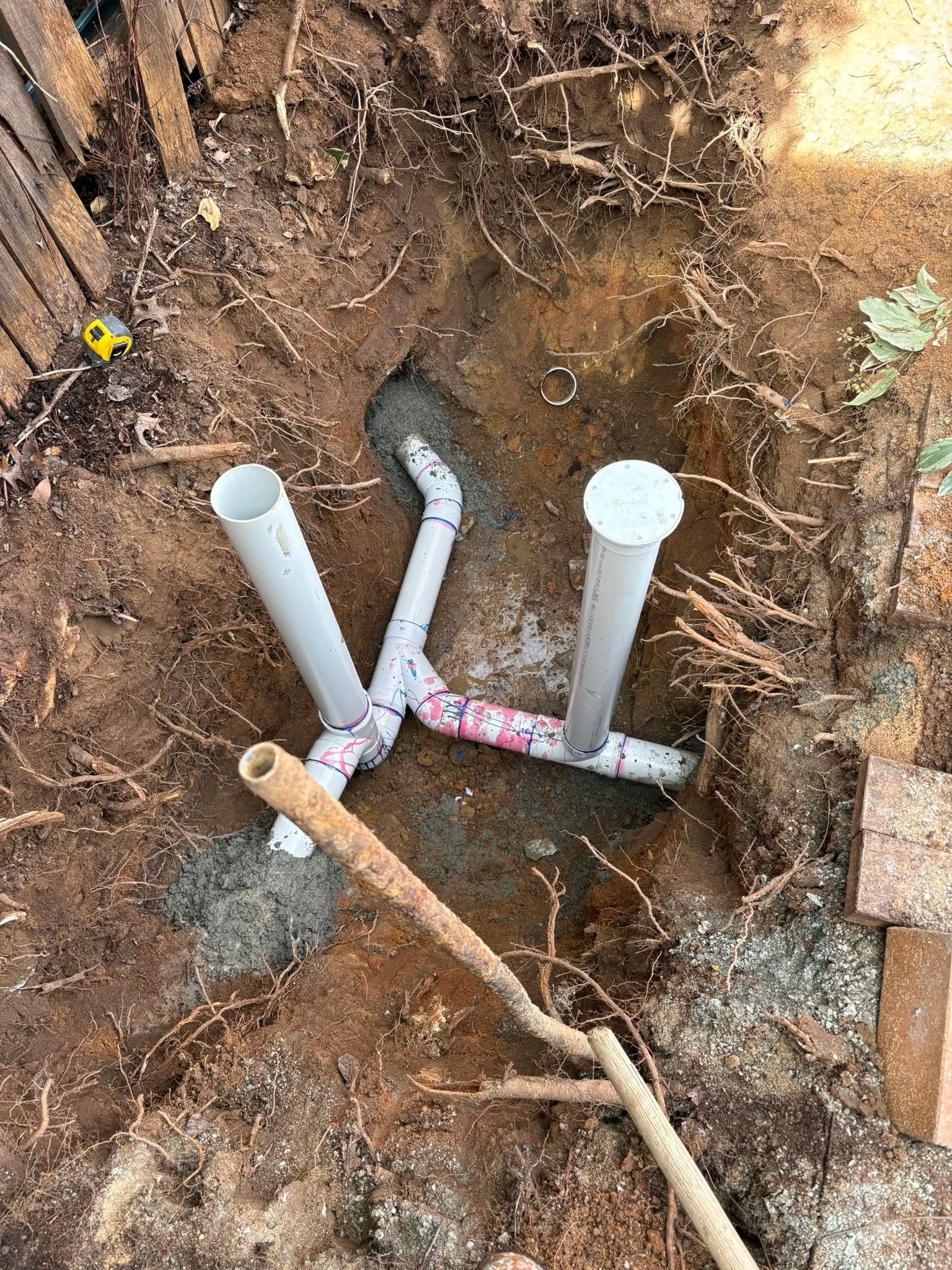 Open Dirt Trench With Exposed Pvc Pipes and Fittings at a Plumbing Worksite — AD Plumbing & Maintenance in Canberra, ACT