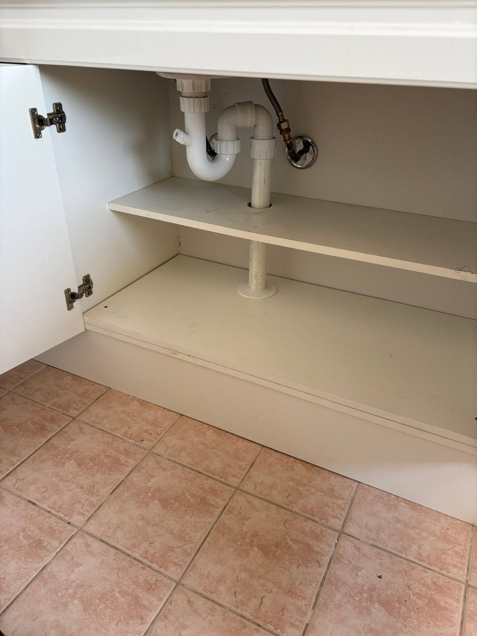 Open Under-sink Cabinet With Shelves, Plumbing Pipes, and Tiled Floor — AD Plumbing & Maintenance in Canberra, ACT