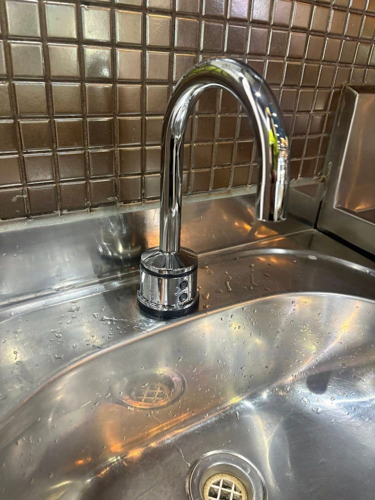 Shiny, Curved Faucet Over a Stainless Steel Sink With a Tile — AD Plumbing & Maintenance in Nicholls, ACT