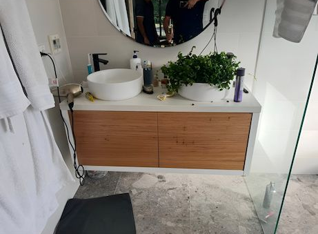 Bathroom With Two Sinks, a Wood-grain Cabinet, and a Large Round Mirror — AD Plumbing & Maintenance in Nicholls, ACT