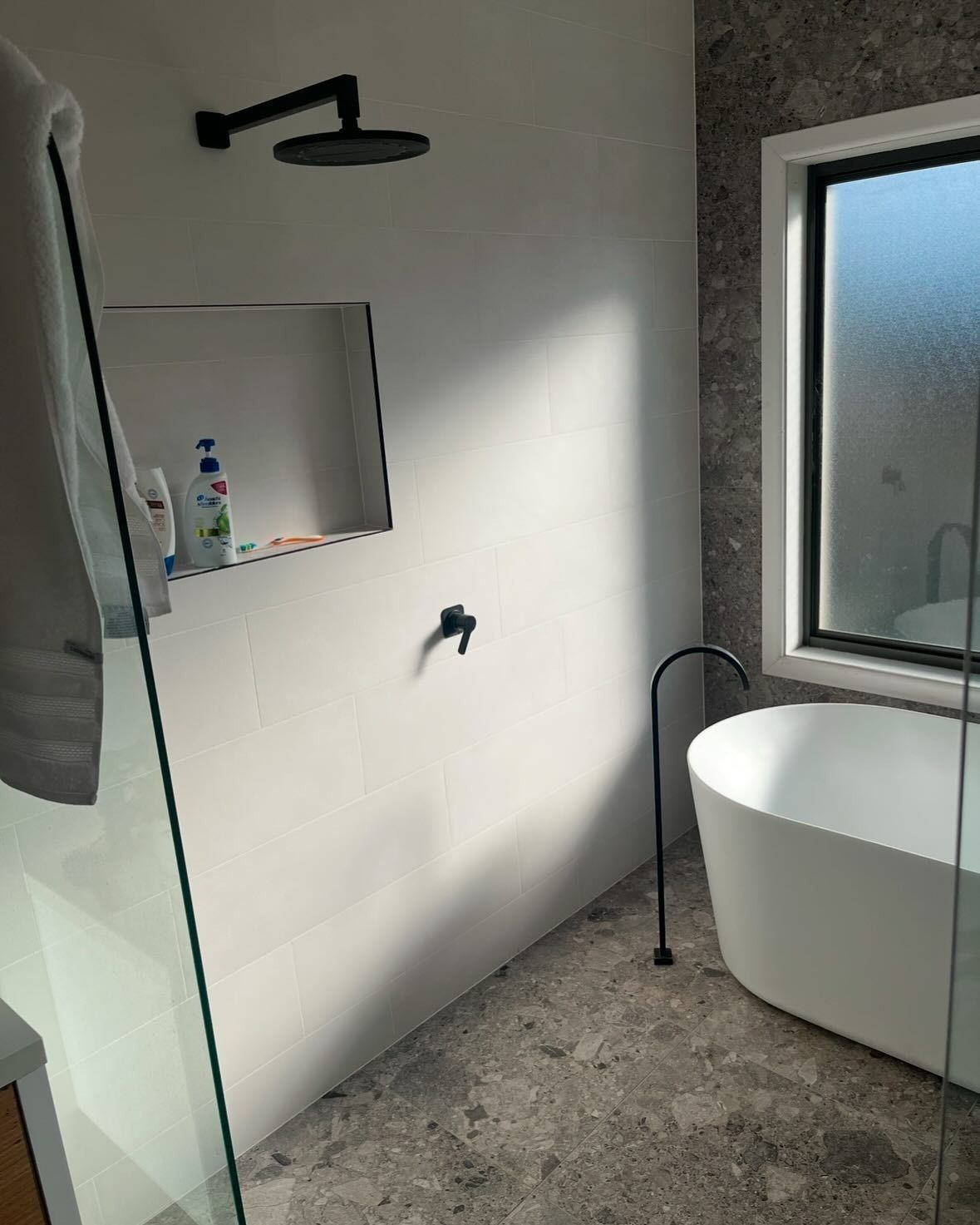 Bathroom With Freestanding Tub, Black Fixtures, Wall Mirror, and Frosted Window — AD Plumbing & Maintenance in Canberra, ACT