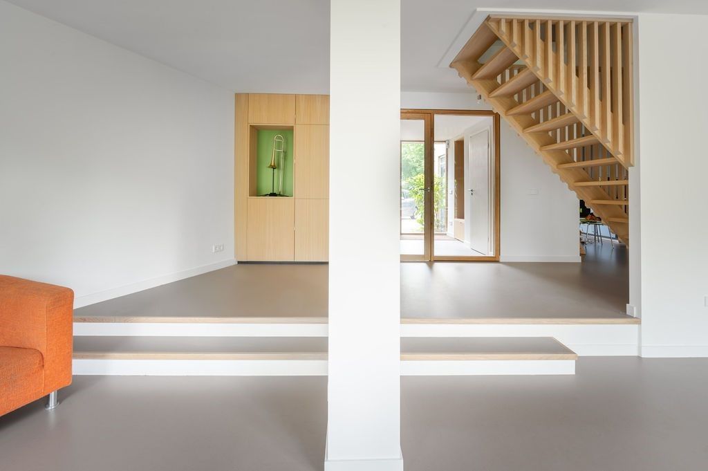 Een woonkamer met een oranje bank en een houten trap