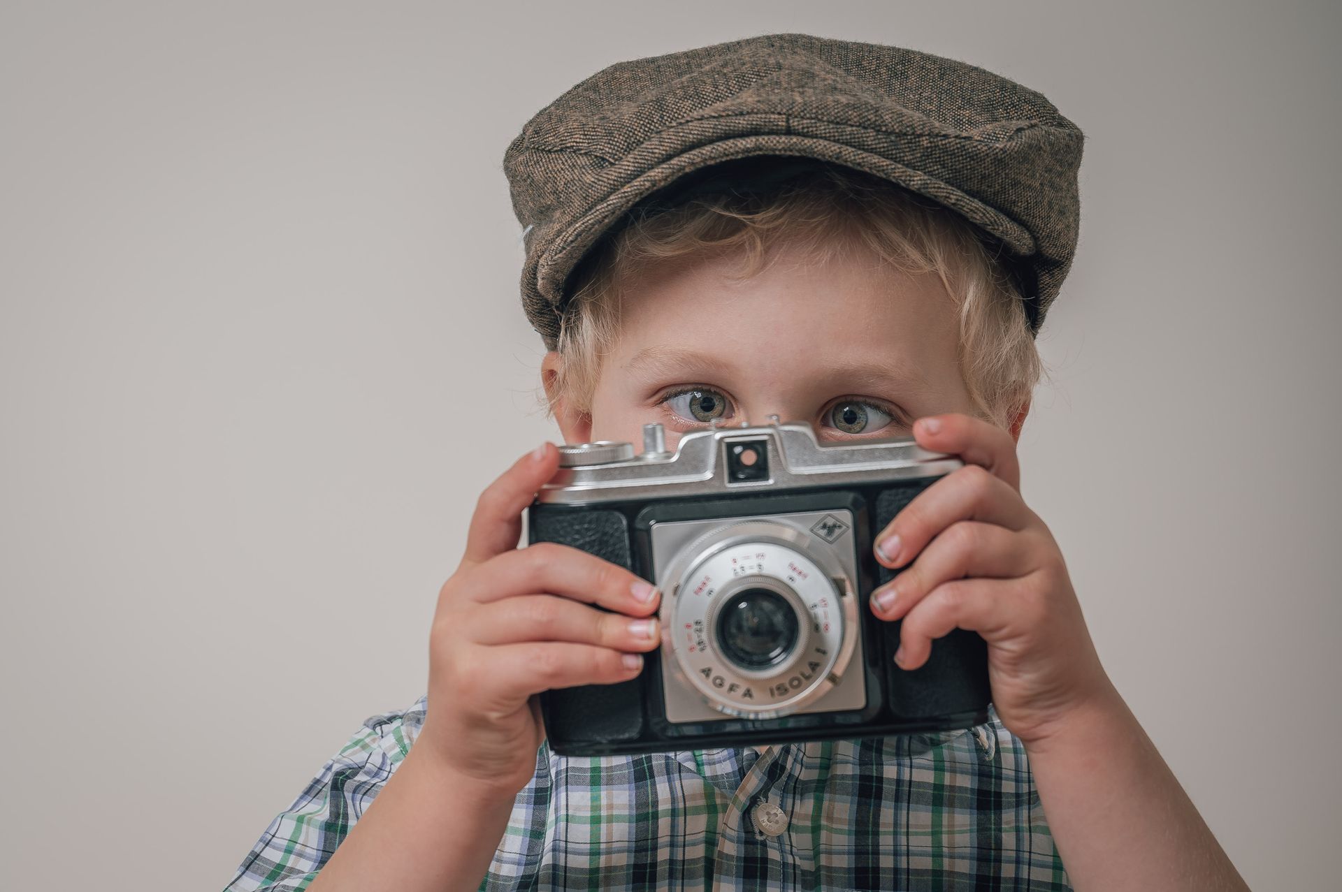 Een jonge jongen met een hoed maakt een foto met een oude camera. M-stand fotografie
