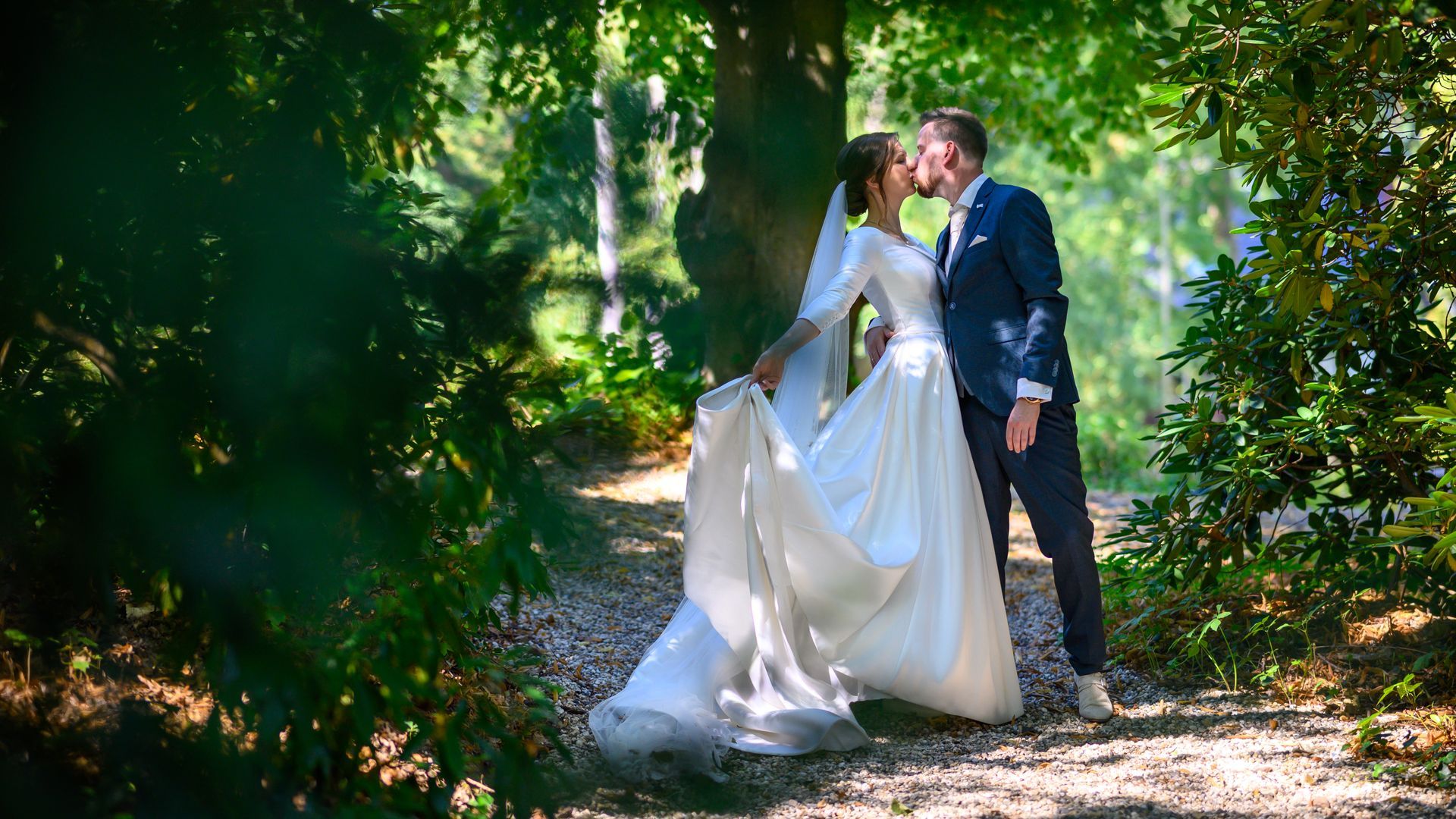 Een bruid en bruidegom kussen elkaar in het bos. M-stand fotografie