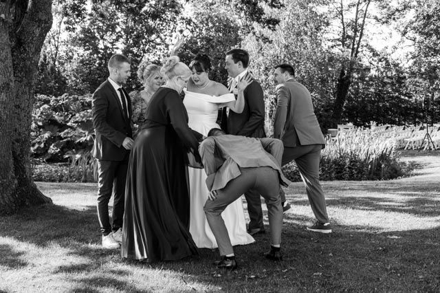 Een groep mensen staat rond een bruid en bruidegom. M-stand fotografie