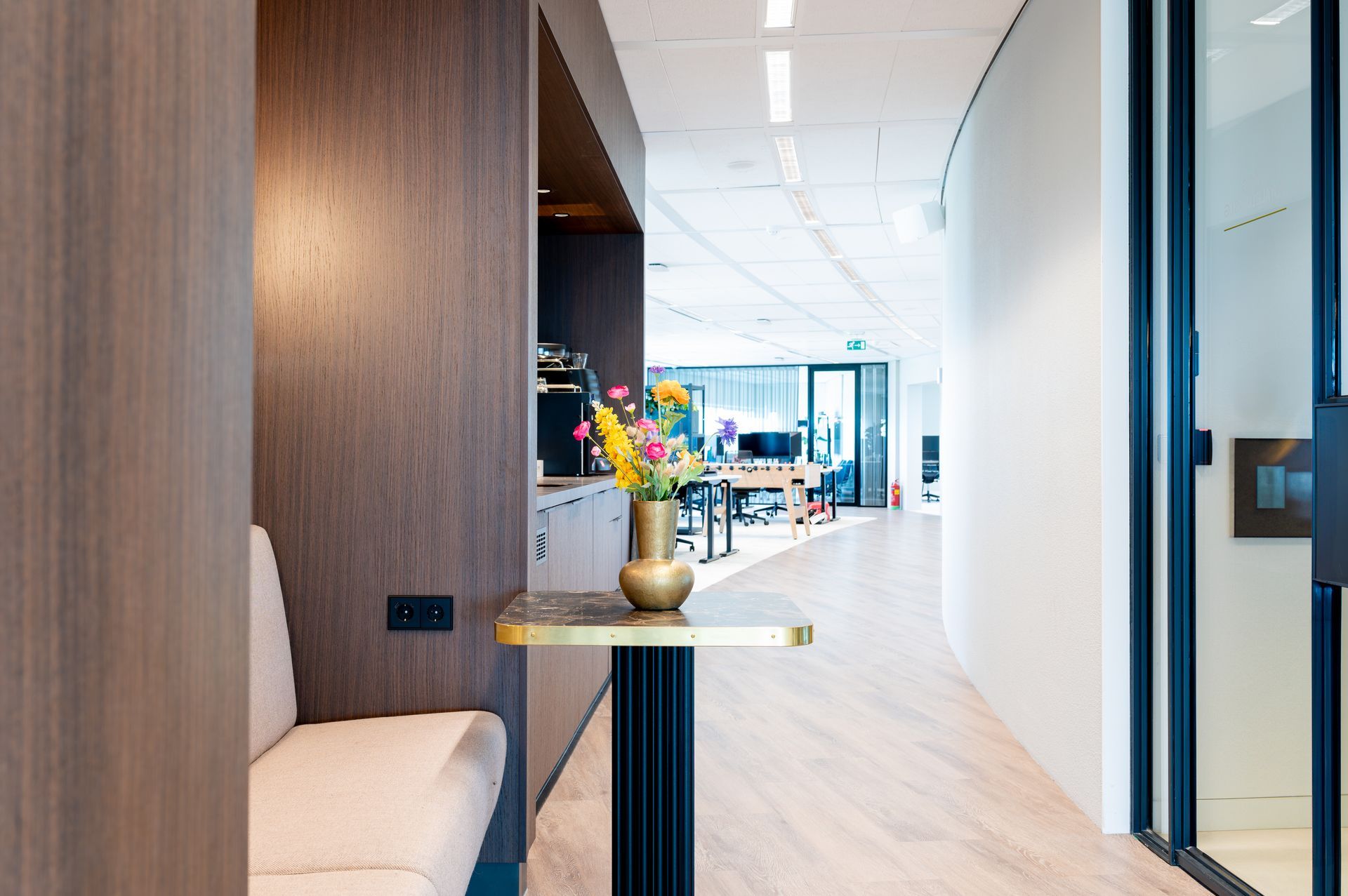 Een tafel met een vaas met bloemen erop in een gang.M-stand fotografie