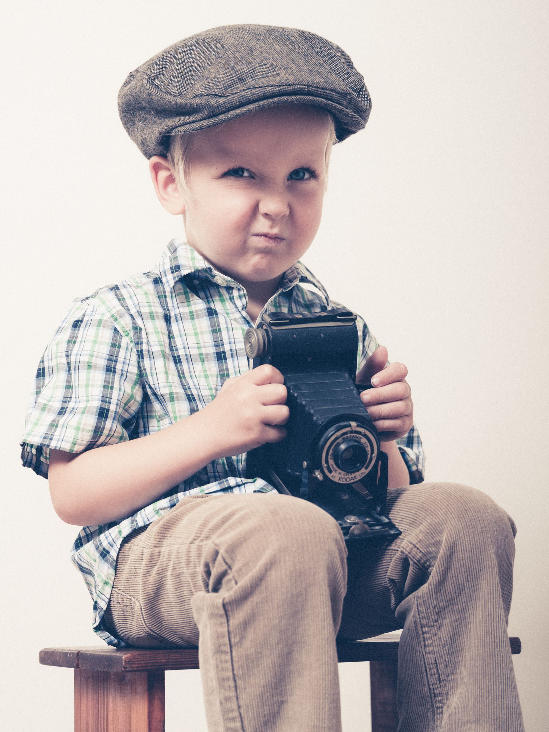 Een jonge jongen met een hoed houdt een camera vast Portretten  M-stand fotografie