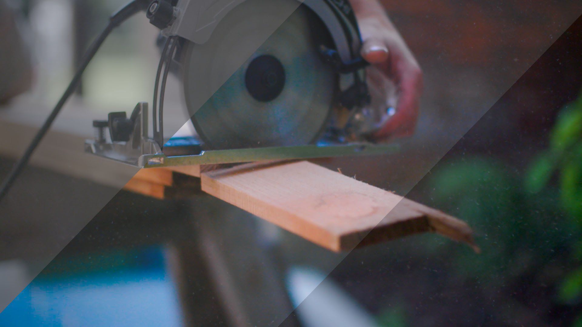 A person is using a circular saw to cut a piece of wood.