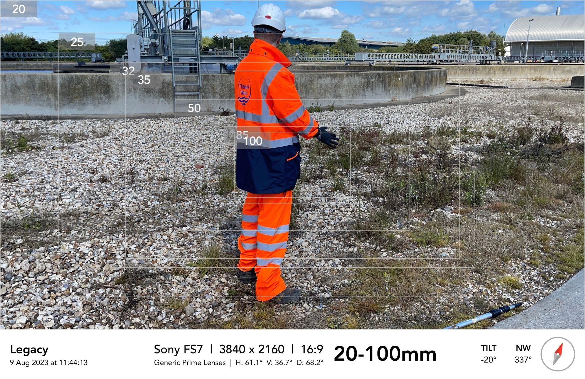 A man in an orange safety vest is standing in a field