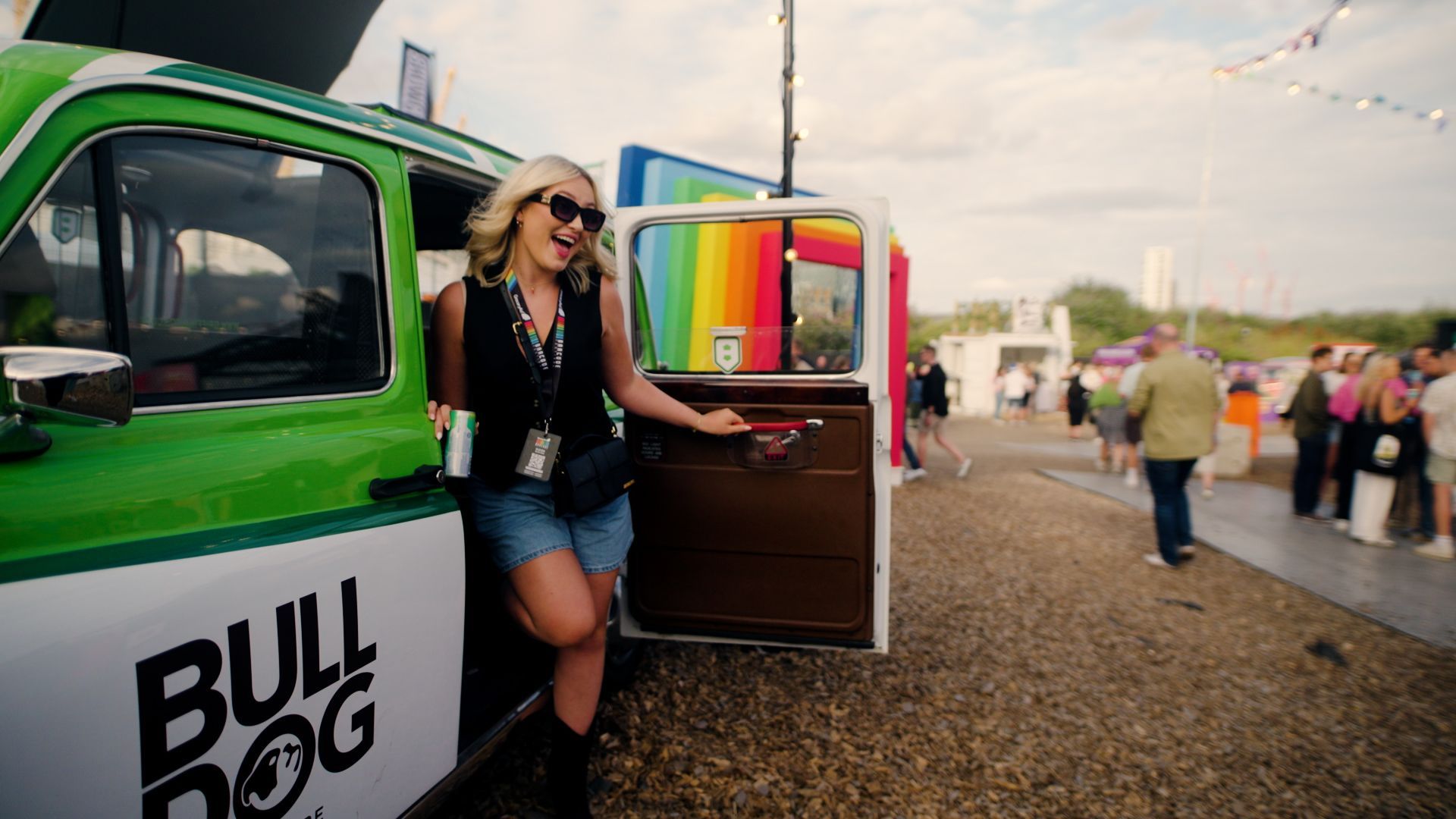 A woman stands in the open doorway of a green taxi.