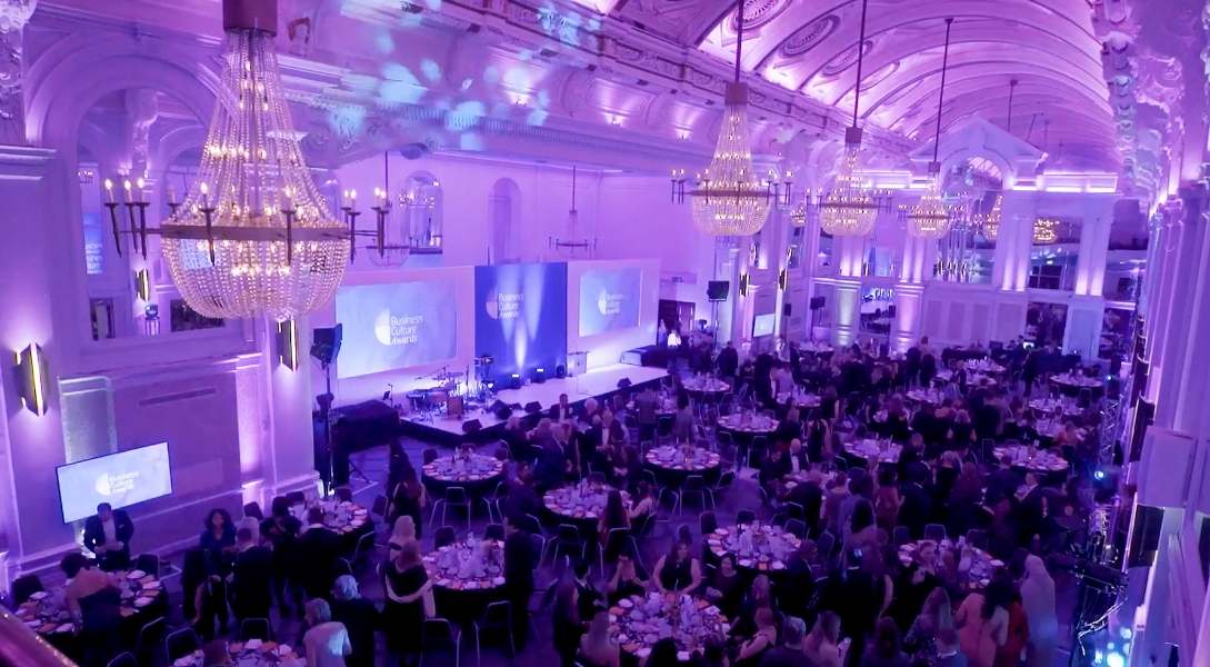 A large room filled with tables and chairs and purple lights.