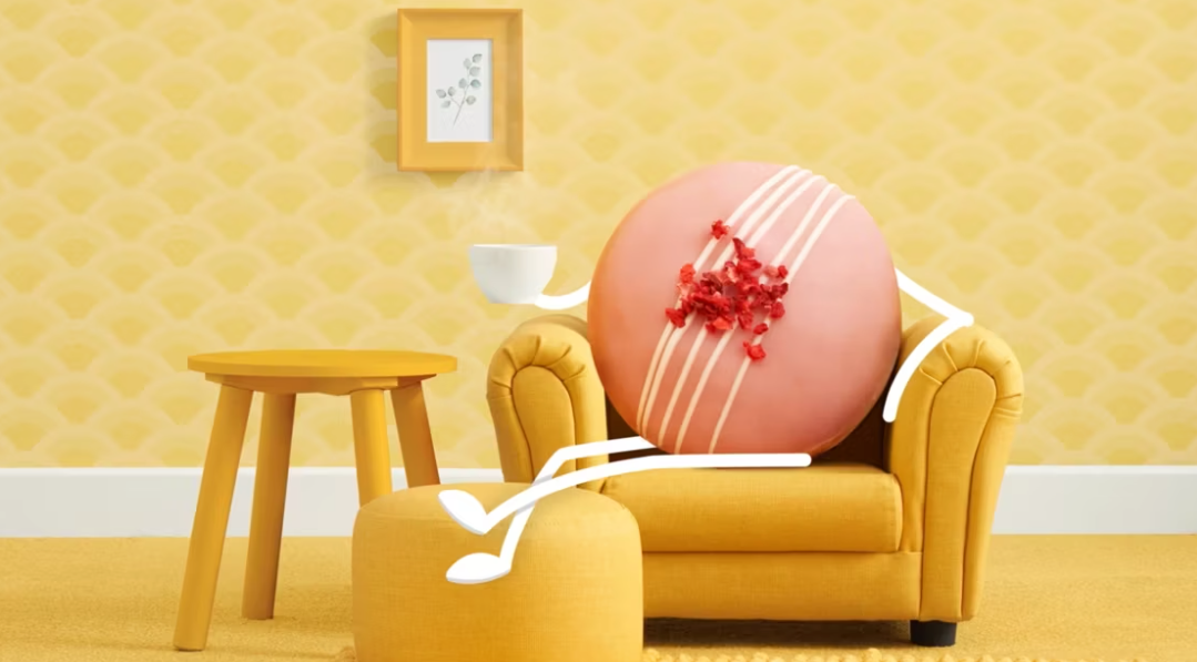 A donut is sitting on a yellow couch in a living room.
